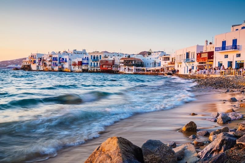 Waves break near the famous buildings of Little Venice in Mykonos at sunset