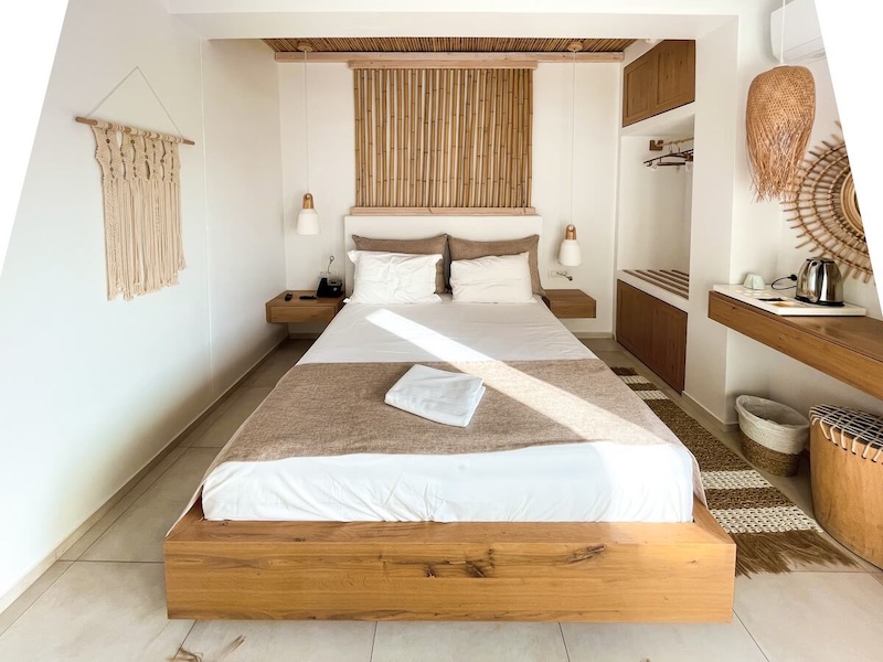 A bedroom at Aktaion Boutique Hotel, with boho white and warm neutral decor and plenty of natural textures.