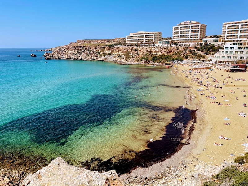 Bright turquoise water at Golden Beach, with big hotels on the other side of the sands.